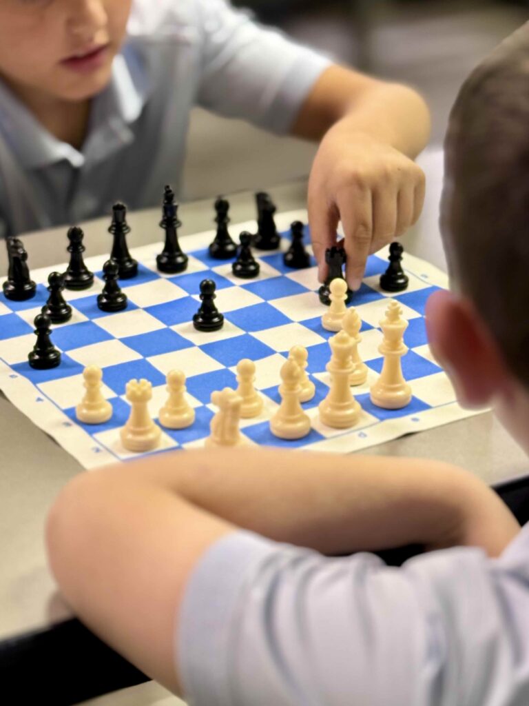 Two boys playing chess, focusing on the board and pieces